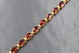 A 14ct gold garnet and diamond set tennis bracelet, the twenty-two oval cut garnets interspersed