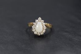 A 9ct gold opal and cubic zirconnia pear cluster ring having a central cabochon opal within a