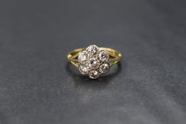 An 18ct gold diamond set daisy cluster ring, the central round brilliant cut diamond measuring