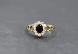 A 9ct gold sapphire and cubic zirconia set cluster ring, the oval cut sapphire in a ten cubic