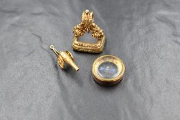 A 9ct gold cannon charm, having spinning wheels, marked 9ct (1.6g), along with a 9ct gold mounted