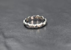 A platinum diamond set band, the wave motif band having three diamond chips, marked 950, ring size