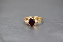 A yellow metal garnet & cubic zirconia ring having a central oval garnet flanked by two small