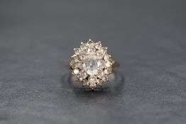 A 9ct gold white sapphire set cluster ring, the central oval cut sapphire in a step layer