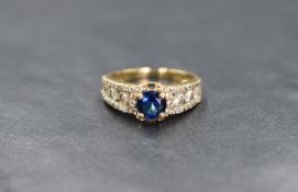 A yellow metal presumed gold cubic zirconia set ring, the central blue cubic zirconia in a clear