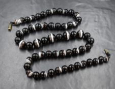A 19th century banded agate bead necklace, the graduated beads of circular form on black thread with