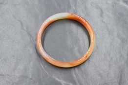 A carved banded agate bangle, having orange and white tones, 6cm internal diameter, 19.6g