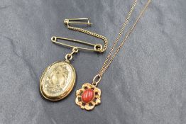 A gold plated locket on a yellow metal presumed gold safety pin having indistinct marks, along