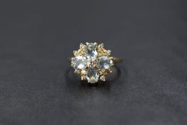 An 18ct gold aquamarine and diamond set floral cluster ring, the central round brilliant cut diamond