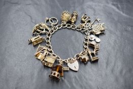 A silver curb link charm bracelet, having seventeen silver and white metal charms, including a