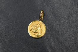 A small 18ct gold circular pendant having a moulded religious scene, approx 2.2g