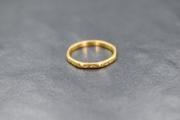 A 22ct gold wedding band of shaped form, decoration worn, size J & 1.7g