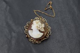 A 9ct gold mounted cameo brooch, depicting a maiden in profile with floral hair accessories, in a