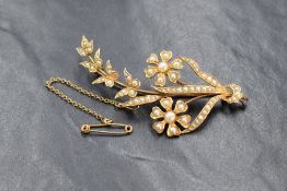 An Edwardian yellow metal seed pearl set floral spray brooch, no marks but tests as 15ct gold,