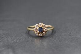 A 9ct gold sapphire and diamond set daisy cluster ring, the central bezel set sapphire in an eight