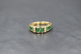 An 18ct gold emerald and diamond set band, the eleven graduated emerald cabochons having two