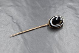 A Victorian yellow metal stick pin having a bulls eye agate cabochon terminal in a collared mount,