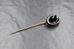 A Victorian yellow metal stick pin having a bulls eye agate cabochon terminal in a collared mount,
