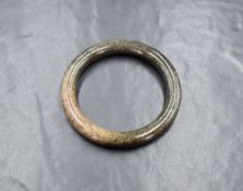 A carved jade bangle, having dark grey-brown tones with fibrous texture visible 5.5cm internal
