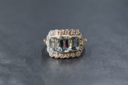 A yellow metal presumed gold aquamarine and diamond set cluster ring, the three graduated emerald