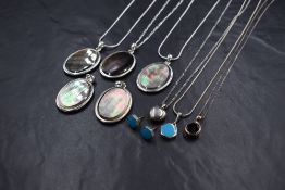 Eight white metal pendants of different forms including abalone shell and small locket, some stamped