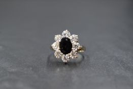 A 9ct gold sapphire and cubic zirconia set cluster ring, the central oval cut sapphire measuring