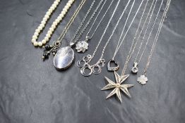 A group of eight silver and white metal necklaces, including an oval locket, cubic zirconia set