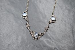 A silver moonstone set necklace, the three oval moonstone cabochons in decorative foliate panels,