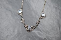A silver moonstone set necklace, the three oval moonstone cabochons in decorative foliate panels,