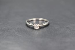 A white metal diamond set solitaire ring, the round brilliant cut diamond in a four claw setting,