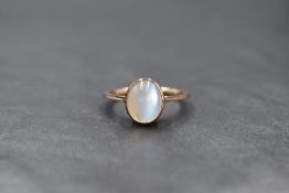A yellow metal presumed gold moonstone set ring, the oval cabochon moonstone in a bezel setting,
