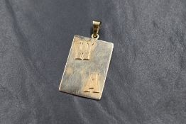 A yellow metal Artisan made pendant of rectangular form bearing an appliqued monogram WA, marks worn