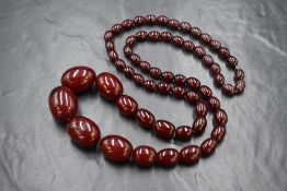 A cherry amber beaded necklace, the beads of oval form measuring between approximately 3.5cm and