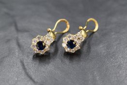 A pair of 18ct gold sapphire and cubic zirconia set earrings, the central round cut sapphires in a