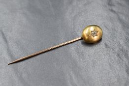 A Victorian yellow metal stick pin of cabochon form having a star set old cut diamond, approx 0.