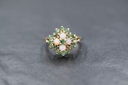 A 9ct gold emerald and opal square cluster having four opal cabochons within a surround of sixteen