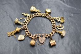 A 9ct gold curb link charm bracelet, having a heart padlock and twelve gold and yellow metal
