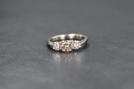 An 18ct white gold diamond set three stone ring, the central round brilliant cut diamond measuring