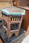 An Eastern style occasional table having hexagonal top with brightly coloured decoration throughout,