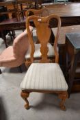 A pair of reproduction vase back dining chairs having overstuffed seats and cabriole legs