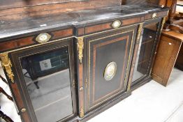 A Victorian ebonised credenza having central enclosed breakfront cupboard flanked by two display