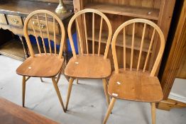 A set of three Ercol hoop and stick back kitchen/dining chairs having H stretcher supports and splay