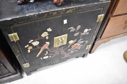 An Oriental style ebonised side cabinet having applique bird and foliate/gilt heightened