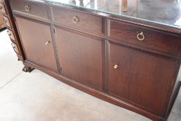 A modern stag sideboard comprising triple frieze drawers with double and single cupboards under,