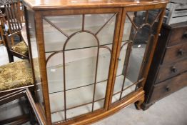 An early 20th Century walnut china cabinet, having glass shelves , on short cabriole legs,