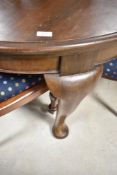An early 20th Century mahogany wind out dining table of circular form, on heavy cabriole legs,