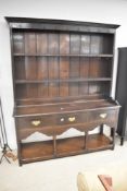 A traditional period oak dresser comprising plate rack over three drawer base with open undertier,
