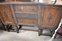 An early 20th Century oak sideboard having three central drawers flanked by cupboards, on bulbous