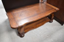 A modern oak heavy coffee table having shaped top and undertier on bun feet, approx. 124 x 64cm