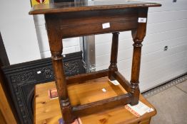 A reproduction oak coffin stool style occasional table by Titchmarsh & Goodwin, labelled to
